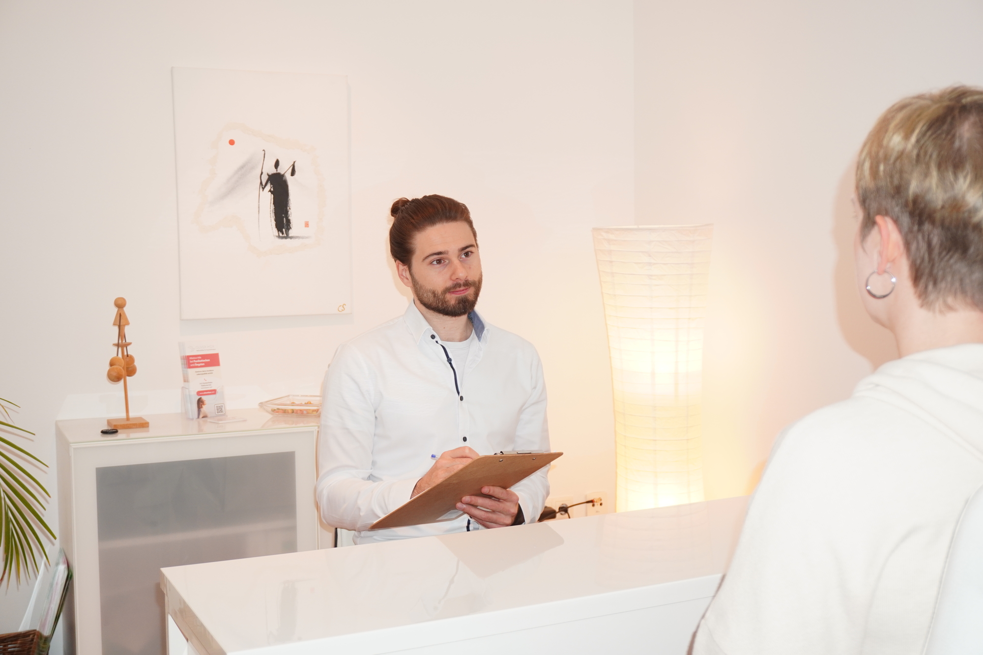 Hypochonder Oliver Hox führt ein konzentriertes Beratungsgespräch mit einer Patientin.