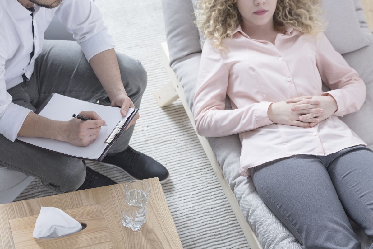 Hypnosesitzung einer Frau, wobei die Frau entspannt auf der Couch liegt.