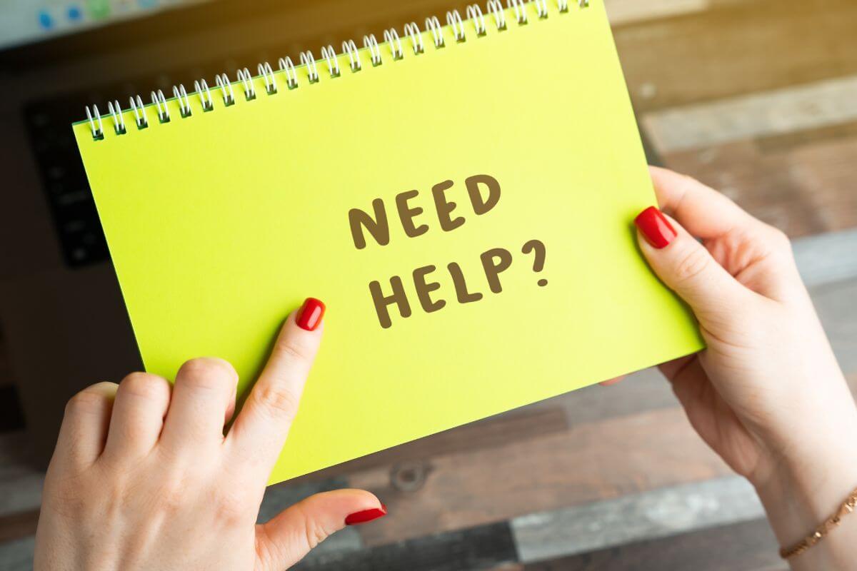 Hände halten einen Notizblock mit der Frage „Need help?“ – Symbol für den Wunsch nach Orientierung und der Frage, ob psychotherapeutische Unterstützung sinnvoll ist.