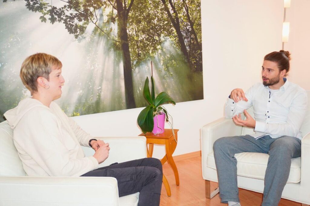 Oliver Hox im Gespräch mit einer Patientin in seiner Praxis in Köln, ruhige Beratungssituation mit Fokus auf Angst und Panikthemen.